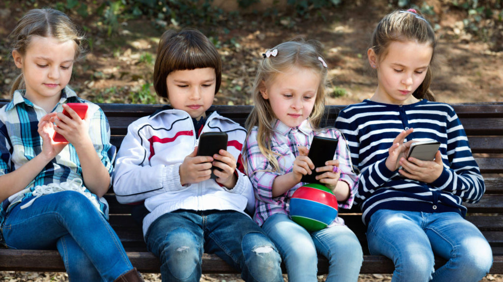 kinderen op een parkbankje met een smartphone